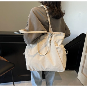 Detail view of cream canvas tote bag showing side pockets and multi-strap design