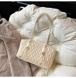 Detail of soft cream pleated tote bag featuring intricate texture on a cozy background