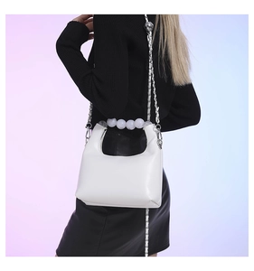 Détail du sac hobo blanc avec une poignée en perles et une bandoulière chaîne argentée