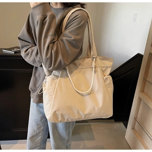 Detail of beige canvas tote bag with drawstring side pocket and metallic snap button