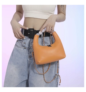 Detail of orange leather shoulder bag with beaded handle and silver chain strap