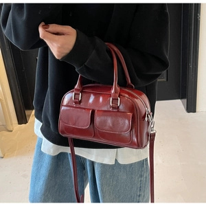 Close-up of wine red oil wax leather Boston bag with silver buckles and dual pockets