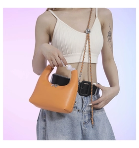 Detail of orange dumpling bag with pearl handle and adjustable gold chain strap