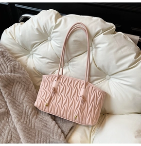 Detail of light pink pleated tote bag with woven texture and elegant gold hardware accents