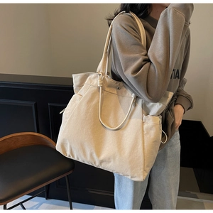 Close-up of minimalist large-capacity canvas tote bag with side pockets in beige color
