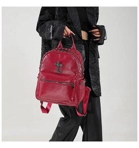 Detail of burgundy gothic backpack featuring silver rivets and metal cross pendant