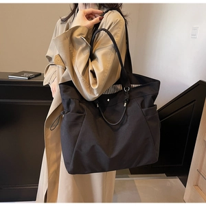 Detail view of large black tote bag side drawstring pocket and reinforced metal rings