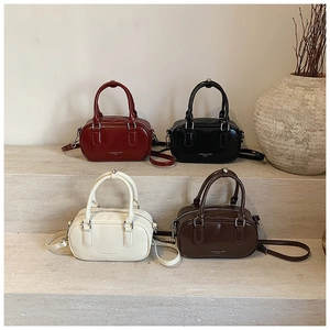 Vue détaillée de quatre mini sacs Boston en rouge noir blanc et marron sur marches en pierre