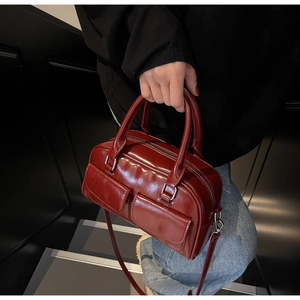 Detail of burgundy wax leather Boston bag with square pockets and round top handles