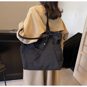 Rear view of model with black minimalist tote bag featuring side pockets and knot detail