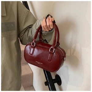 Détail du sac Boston en cuir verni bordeaux avec garnitures argentées et poignées