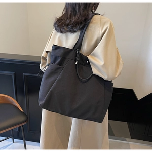 Detail view of the functional side drawstring and nylon texture on a black tote bag