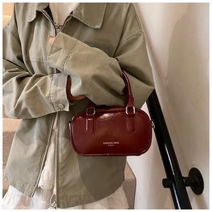 Détail macro du sac en cuir verni bordeaux avec anneaux de poignée en métal argenté