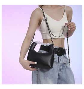 Detail of black leather dumpling bag with white frosted beaded handle and silver chain strap
