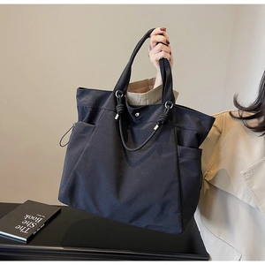 Detail of black nylon tote bag showing durable side pockets and stylish knotted handles