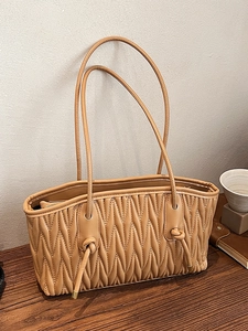 Caramel pleated leather tote bag with quilted V-pattern and long top handles in lifestyle view