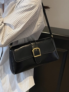 Sac baguette noir avec boucle carrée dorée porté sur une chemise à rayures bleues