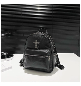 Detail of black glossy PU leather backpack featuring silver rivets and cross pendant