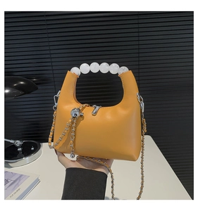 Detailed shot of yellow dumpling bag with large pearl handle and silver chain strap