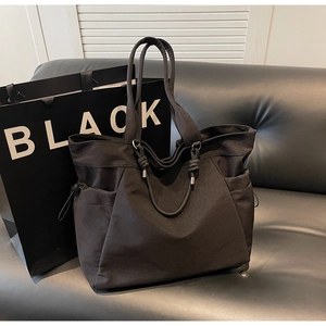 Detailed side view of black large capacity tote bag with drawstring side pockets and knot handles