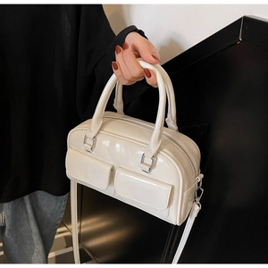 Detail of cream white faux leather Boston bag with double handles and front flap pockets