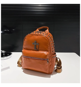 Detail view of orange punk backpack with vintage metal cross and silver rivet studs
