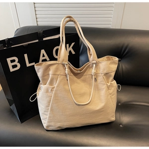Detail of beige canvas tote bag with drawstring pockets on black leather background