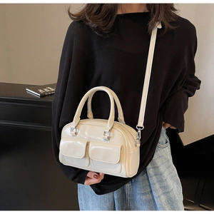 Close-up of cream wax leather Boston bag with dual front pockets and silver hardware