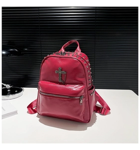 Detail showing red leather backpack with metal studs and a cross chain pendant