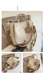 Detail der weißen PU-Beuteltasche mit U-förmigem Metallgriff und floralem Anhänger