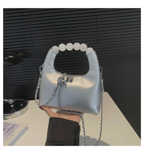Detail view of silver metallic crossbody bag featuring five large frosted bead handles