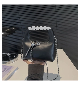 Detail of black crossbody bag with white bead handle and silver metal chain strap