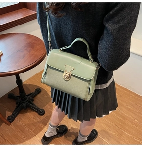Detail der graugrünen Tasche mit Webstruktur, glatter Klappe und goldener Schnalle