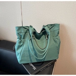 Detail view of large dark green tote bag with side drawstrings and button closure