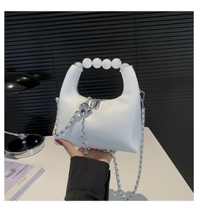 Detail of white PU leather bag featuring large pearl beads handle and metal chain accent