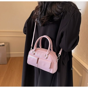 Pink oiled leather Boston bag styled with a long black coat for a trendy commuter look