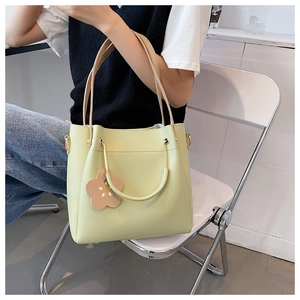 Detail der pistaziengrünen PU-Beuteltasche mit goldenem Metallgriff und Blumenanhänger