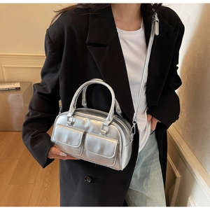 Detail of silver metallic Boston bag featuring dual front pockets and glossy oil wax leather