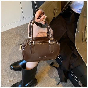 Détail d'un sac Boston marron brillant vintage avec fermeture éclair et doubles poignées