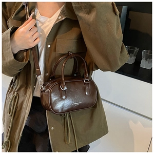 Détail macro du sac à main en cuir marron brillant avec lettrage et surpiqûres précises