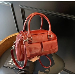 Detail view of the glossy wine red Boston bag showing front pockets and leather texture