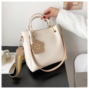 Detail der cremefarbenen Beuteltasche mit Goldbeschlägen und Streifenschultergurt