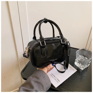 Détail du sac Boston noir brillant avec doubles poignées et fermeture éclair argentée