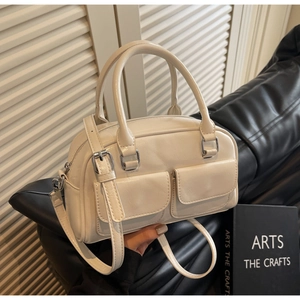Detail of cream oil-wax leather Boston bag with dual front pockets and silver metal buckles