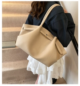 Close-up of beige lychee grain leather tote bag with elegant pleated detail and metal buckle
