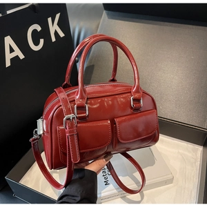 Detail of red patent leather Boston bag featuring front flap pockets and silver hardware