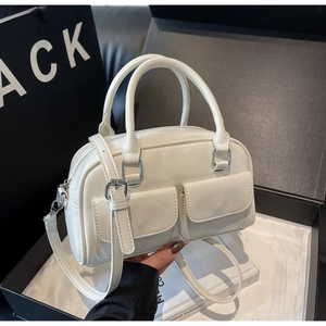Detail view of white gloss faux leather Boston bag with double flap pockets and silver hardware