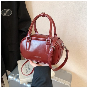 Détail d'un sac cylindre bordeaux élégant en cuir verni avec logo de marque