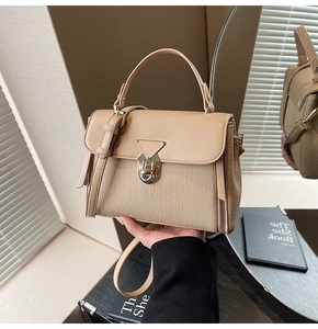 Detailansicht der beigefarbenen gewebten Handtasche mit Metalldreieckschloss und Reißverschluss