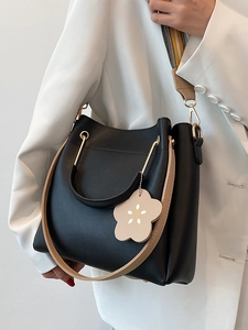 Minimalistische schwarze Leder-Eimertasche mit Kontrastgurten am Modell gezeigt